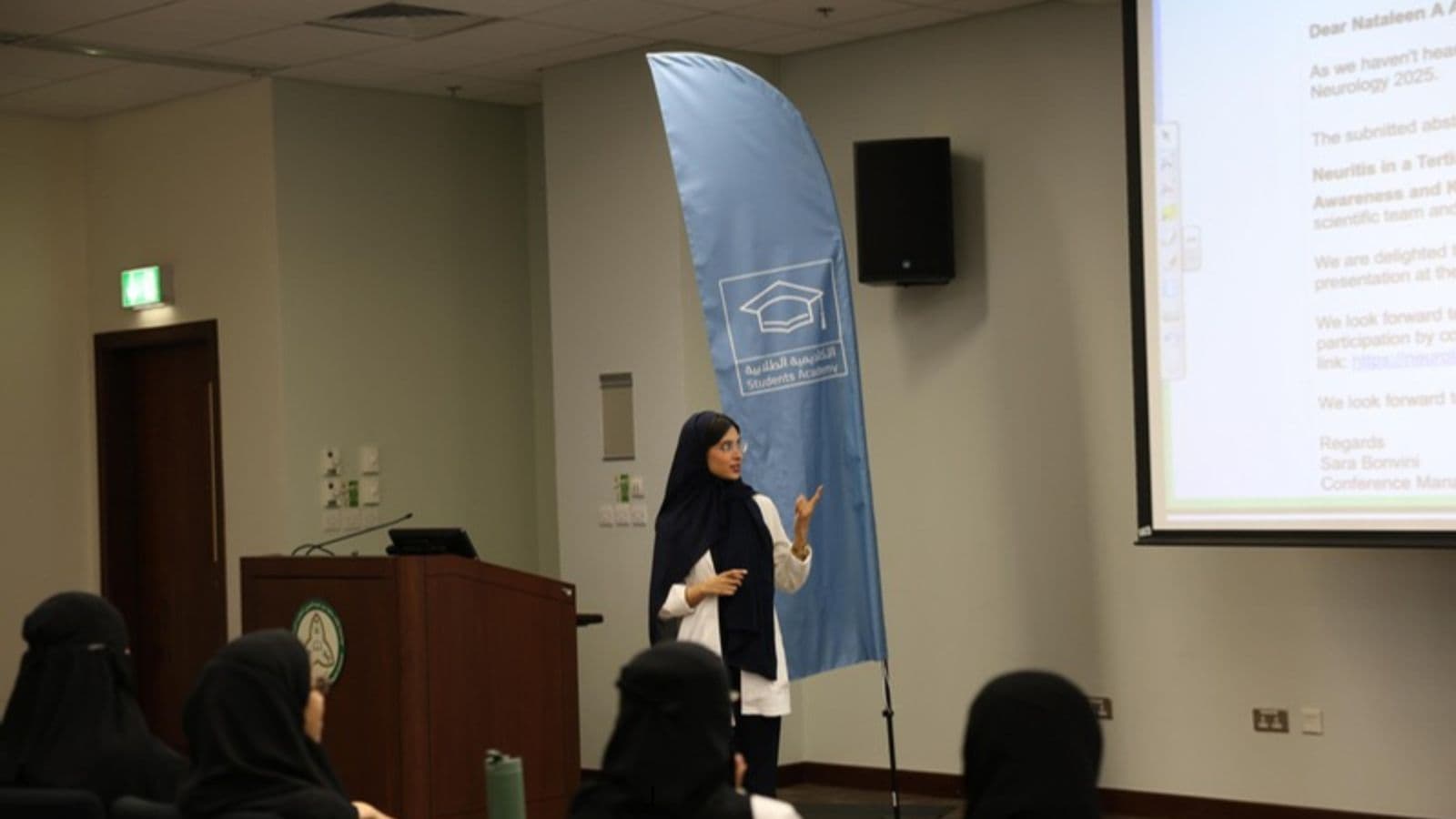 A student presenting beside a Student Academy banner