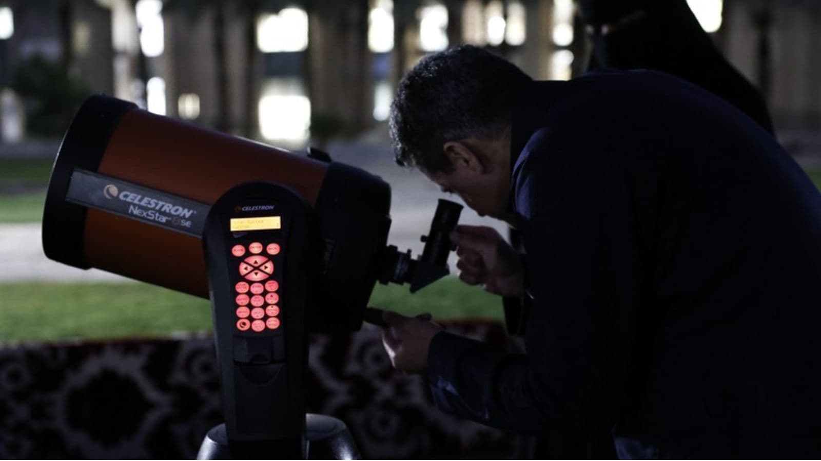 An astronomy club member observing the sky through a telescope at a Student Academy event